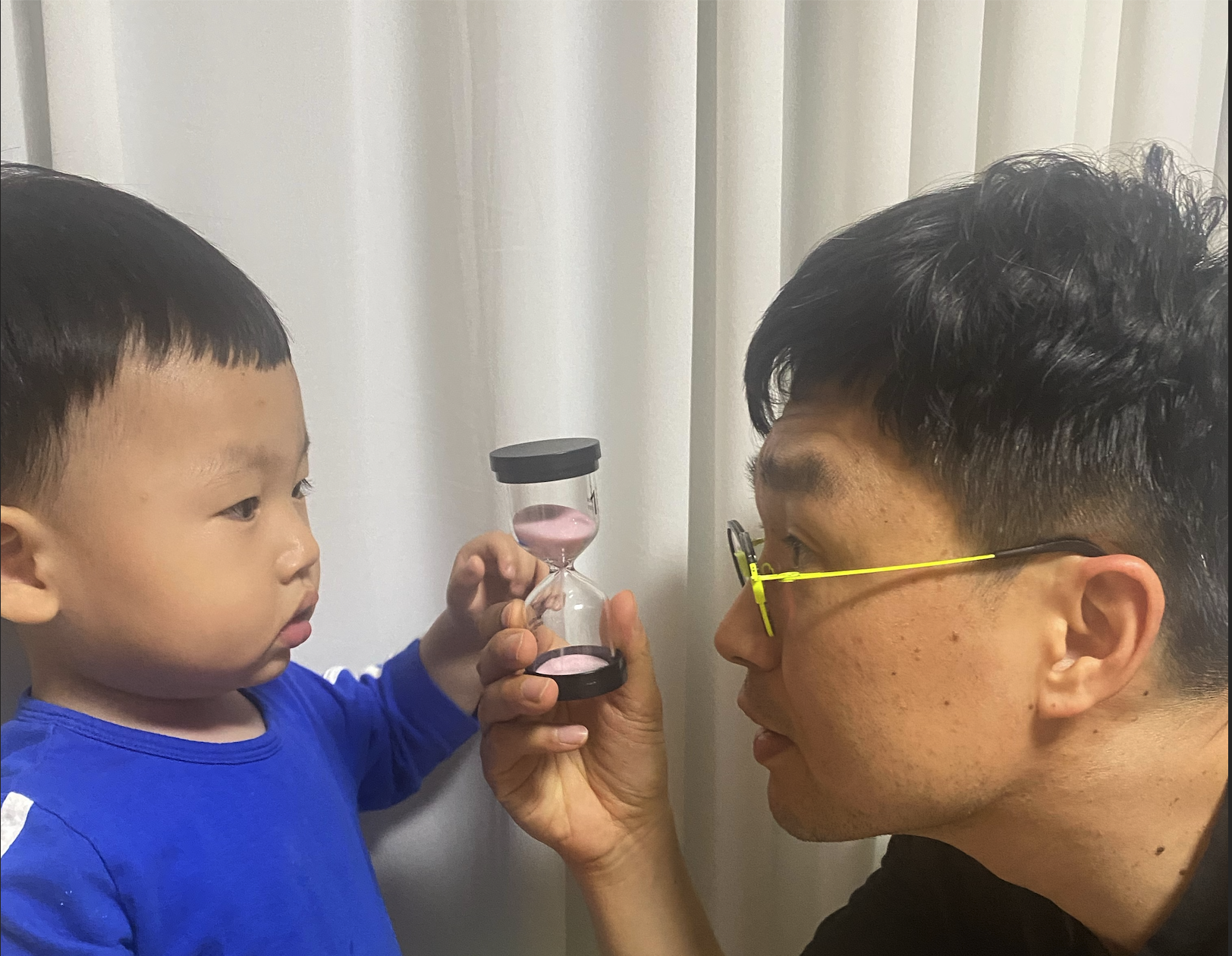 아이와 모래시계를 함께 바라보며 눈높이를 맞추는 박철홍 원장